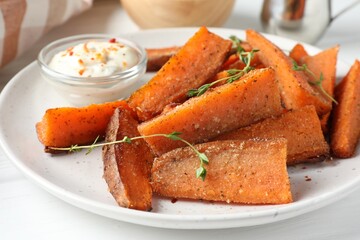 Pieces of tasty baked sweet potato with microgreens served on white table, closeup