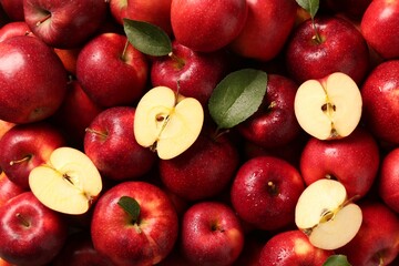 Fresh ripe red apples and green leaves as background, top view