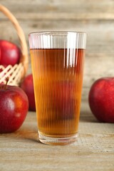 Glass of juice and apples on wooden table