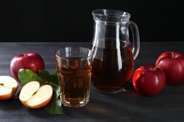 Tasty fresh apple juice and fruits on black wooden table
