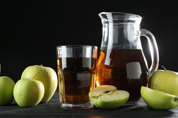 Tasty fresh apple juice and fruits on black wooden table