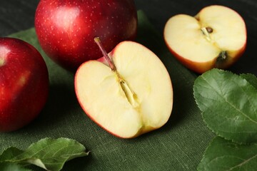 Fresh ripe red apples and green leaves on grey table, closeup