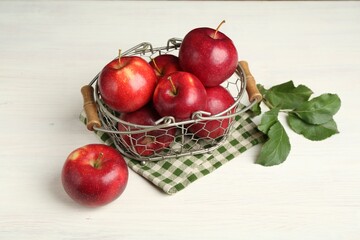 Fresh ripe red apples and green leaves on white wooden table
