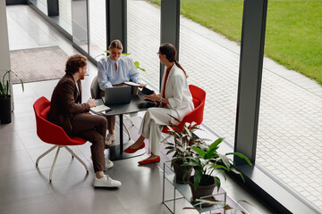A vibrant brainstorming session occurs in a bright office with plants and large windows, enhancing creativity