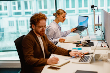 Professionals are collaborating in a brightly lit office space while analyzing data on their...