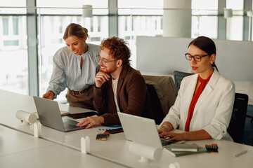 Team members are collaborating with their laptops in a bright, modern, and contemporary office space filled with light