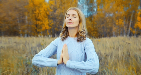 Calm relaxed healthy woman meditates, girl practicing doing yoga exercises outdoors, stress relief