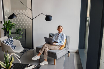 A professional woman diligently working on a laptop in a stylish and contemporary office environment