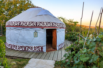 A round tent sits in a field, kyrgyz authentic nomadic yurt