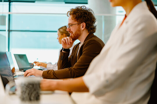 Professionals are actively engaged in effective teamwork while using their laptops in a modern work environment