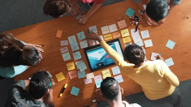 Time lapse of programmer brainstorming and planning about web design while looking at tablet wireframe prototype. Aerial view of skilled developer team talking about digital application. Symposium.