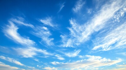 Obraz premium clear blue sky adorned with wispy white clouds, creating a serene and tranquil atmosphere.
