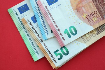 Big amount of one hundred, twenty, ten and fifty euro money bills on red background