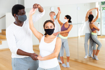 Group of multinational activity people in protective masks practicing dance techniques