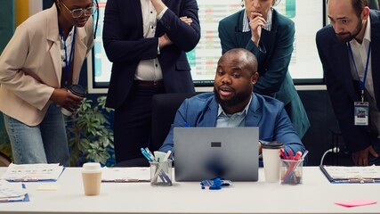 Diverse corporate employees analyzing project updates to ensure goal accomplishment, reviewing infographics on laptop and finding ways to obtain new funds. Business management team. Camera A.