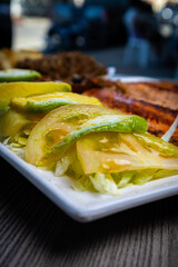 Green Tomato and Lettuce Salad: A fresh, vibrant salad in the foreground. Behind it, a grilled trout and fried rice, slightly blurred, add depth and texture, highlighting the salad's crispness