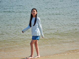 夏の海のビーチで散歩する一人の小学生の女の子の姿