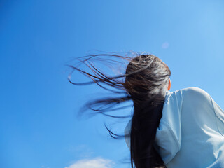 夏の綺麗な青空と屋外で楽しく遊んでいる小学生の女の子の様子