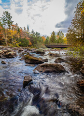 Raquette River Long Lake NY ADK surrounded by brilliant fall foliage on a partly cloudy day