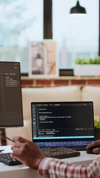 Vertical Video Male coder works from home typing code on a laptop in a modern living room. African american IT engineer using programming language and cloud computing for software development. Camera