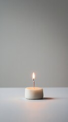 A small birthday cake with a single candle on plain background