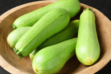 Fresh zucchinis in bowl on table, closeup