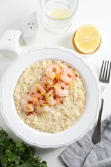 Delicious risotto with shrimps and cheese served on white table, top view