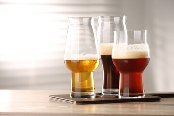 Glasses with different types of beer on wooden table indoors, closeup. Space for text