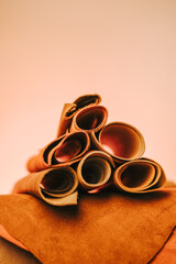 leather assortment. Natural brown leather pieces and rolls against an orange-hued background.