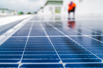 A worker in an orange safety jacket inspects solar panels on a rooftop, using a laptop to ensure...