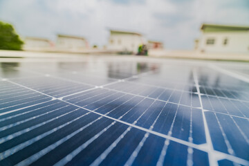 A close up of solar panels with a worker blurred in the background. The focus on the panels emphasizes the importance of renewable energy technology and solar power installations.