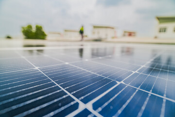 Fototapeta premium A close up of solar panels with a worker blurred in the background. The focus on the panels emphasizes the importance of renewable energy technology and solar power installations.