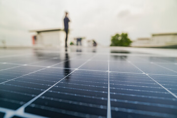 A worker installs or maintains solar panels on a rooftop. The image highlights renewable energy...