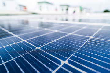 A close up of solar panels with a worker blurred in the background. The focus on the panels emphasizes the importance of renewable energy technology and solar power installations.