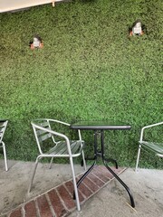 bistro patio seating - silver metal chairs and a small black metal and glass table in front of a green hedge
