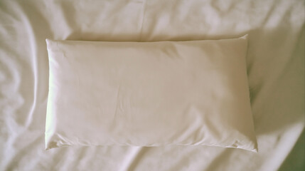 Obraz premium a minimalist, clean top-down view of a soft, rectangular white pillow on smooth white sheets