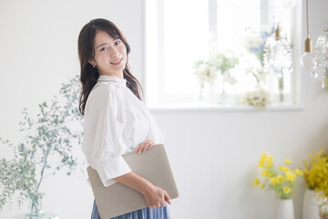 パソコンを持ってカメラ目線で笑顔の若い女性　転職や採用のイメージ