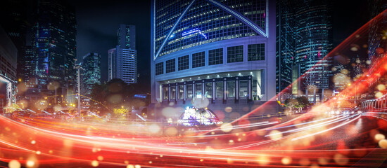 Night time cityscape of Hong Kong, China showing high rise buildings with a tunnel and road with streaks of car lights.