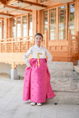 A 9-year-old Korean girl wearing a hanbok is performing a traditional dance in front of a traditional building in the historic town of Gyedong-gil, Jongno District, Seoul, Korea.