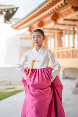 A 9-year-old Korean girl wearing a hanbok is performing a traditional dance in front of a traditional building in the historic town of Gyedong-gil, Jongno District, Seoul, Korea.