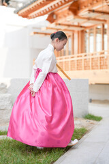 A 9-year-old Korean girl wearing a hanbok is performing a traditional dance in front of a traditional building in the historic town of Gyedong-gil, Jongno District, Seoul, Korea.