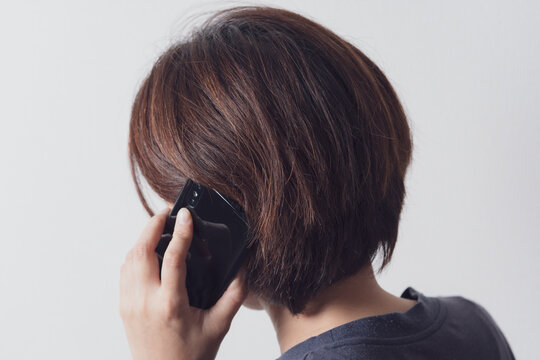 スマホで通話をするアジア人の中年女性の後ろ姿