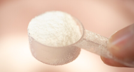 Creatine, food supplement. Macro of a man's hand holding a scoop with creatine.
