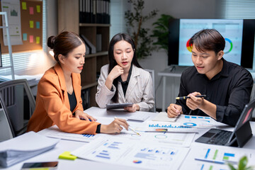 Asian business team analyzing financial graphs and charts in modern office