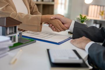 Real estate agent shaking hands with client after signing contract