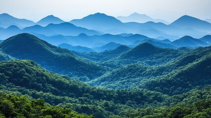 A panoramic view of rolling hills fading into the distance, showcasing layers of blue and green hues against a hazy sky.