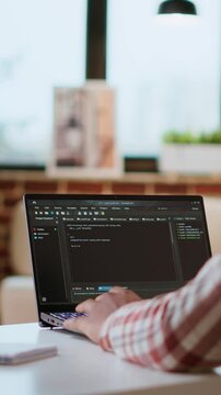 Vertical Video African american software engineer works on a laptop typing code for a development project. Technical specialist multitasking, debugging and using advanced digital tools for coding