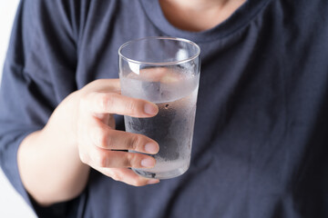 水の入ったグラスを持つアジア人の中年女性の手元