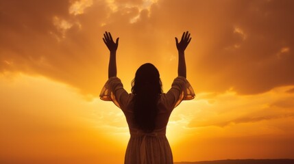 Fototapeta premium A silhouette of a woman in prayer, arms raised against a vibrant sunrise sky, symbolizing faith and spiritual reflection.