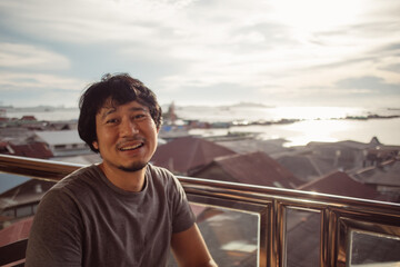 Smile asian man enjoy the happy moment with sunset and sea view.